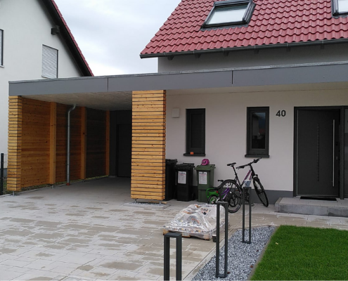 Holzcarport – Referenzprojekt Moderner Holzcarport mit Flachdach an einem Wohnhaus