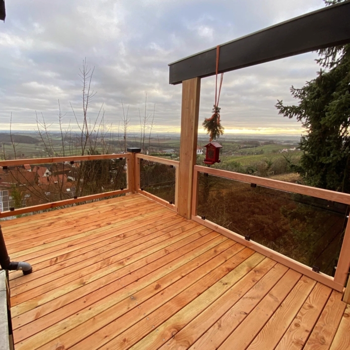 Holzbalkon mit Glasgeländer als Anbau an ein Wohnhaus