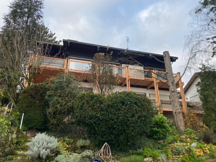 Holzbalkon mit Glasgeländer als Anbau an ein Wohnhaus