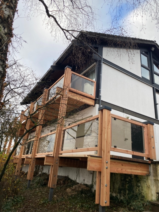 Holzbalkon mit Glasgeländer als Anbau an ein Wohnhaus