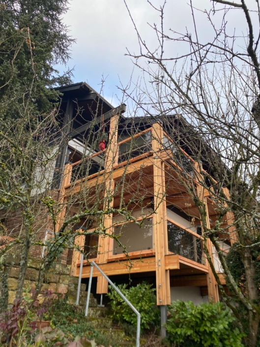 Holzbalkon mit Glasgeländer als Anbau an ein Wohnhaus