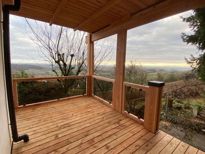 Holzbalkon mit Glasgeländer als Anbau an ein Wohnhaus