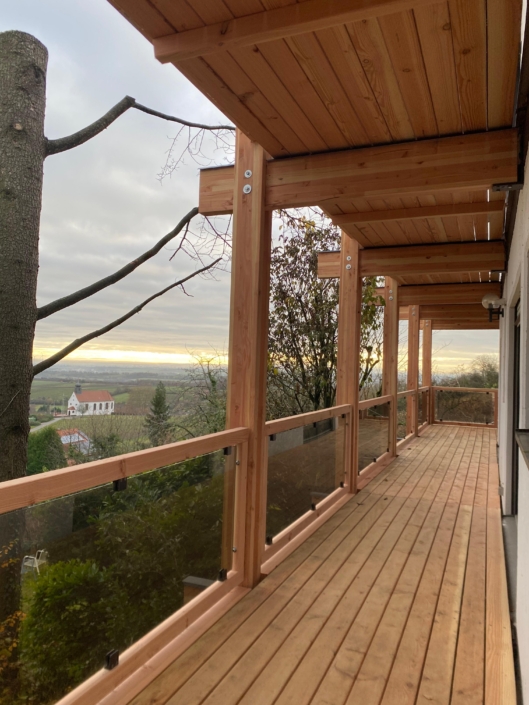 Holzbalkon mit Glasgeländer als Anbau an ein Wohnhaus