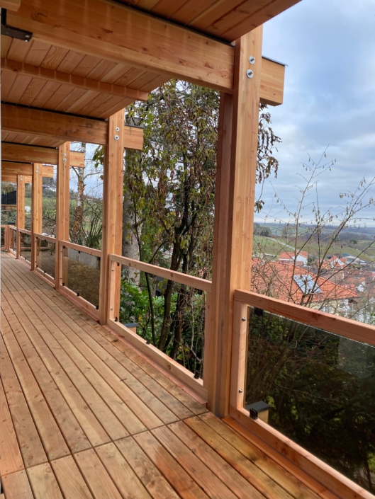 Holzbalkon mit Glasgeländer als Anbau an ein Wohnhaus