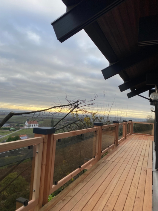 Holzbalkon mit Glasgeländer als Anbau an ein Wohnhaus