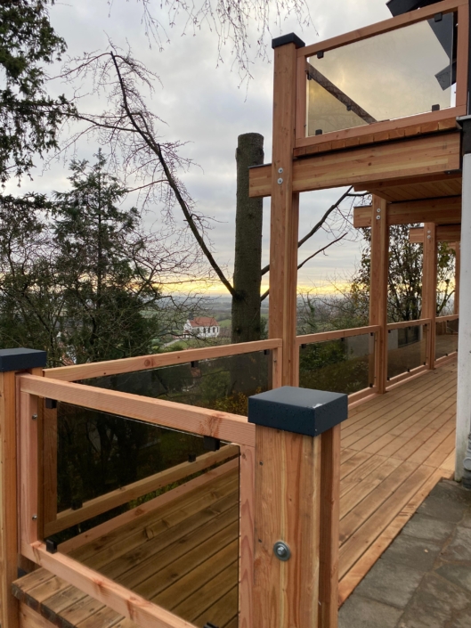 Holzbalkon mit Glasgeländer als Anbau an ein Wohnhaus